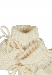 Dziane kremowe buciki z prążkowanym mankietem, sznurkiem do zaciągania oraz naszywką. Miękka tekstura i przytulny design.