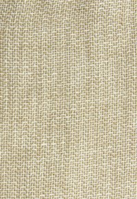 Gros plan d'un tissu beige avec une texture grossière tissée composée de fils épais entrelacés créant un motif en grille.
