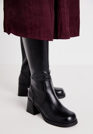 Mustad põlvekohal saapad siledast nahast viimistlusega, neljakandilised kontsad ja külgõmblused, kombineeritud marooni seeliku jaos.