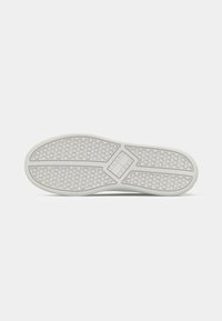 Witte rubberen sneakerzool met een textuurdesign dat ronde grippatronen en hoekige accenten bevat voor grip en stabiliteit.