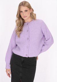 Lavenderfarbener Strickcardigan mit strukturiertem Muster, rundem Halsauschnitt und fünf Knöpfen auf der Vorderseite. Die Ärmel sind leicht oversized.