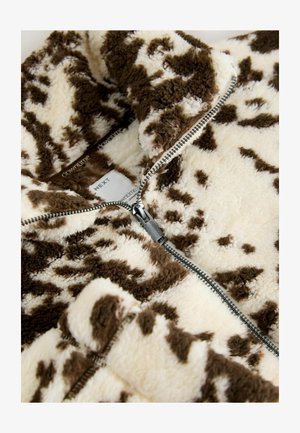 Kurtka z sztucznego futra zapinana na zamek w kolorze kremowym i brązowym, z wypukłą powierzchnią i plamkowanym wzorem oraz srebrnym zamkiem. Widoczna metka.