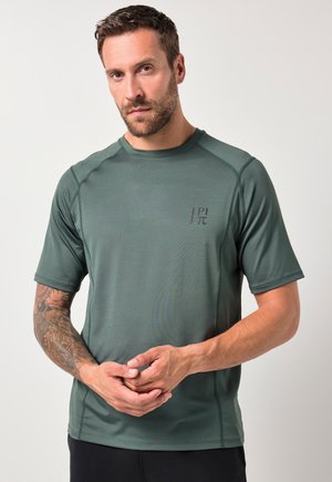 Camiseta atlética de manga corta, de color verde oscuro, fabricada con tejido transpirable, que cuenta con costuras planas y un pequeño logotipo en el área del pecho izquierdo.