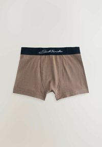 Braune Boxershorts mit einem schwarzen elastischen Bund, auf dem in weißer Schreibschrift "Abonnieren" steht. Glattes Material und eine enge Passform mit einem Frontbeutel.