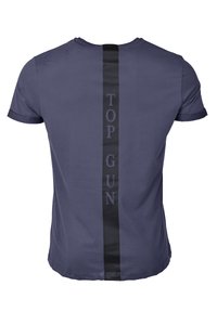 Marinblå t-shirt med kort ärm har ett svart vertikalt rand på baksidan med texten "TOP GUN" i fetstil. Mjuk tygkänsla.