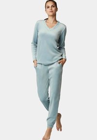 Lichtblauw, fluwelen pyjamajasje met een V-hals en lange mouwen, en een tapered broek met elastische manchetten en zijzakken.