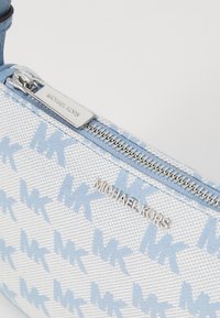 Blue and white canvas pouch with 'MK' pattern, silver zip hardware, and a logo plaque on the side; features a textured surface.
