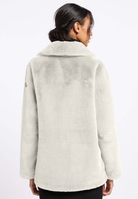 Faux fur jasje in lichtgrijs met een zachte textuur, een notch-kraag en lange mouwen. Heeft een eenvoudig ontwerp met een achterkant.