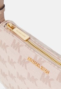 Beige stoffpung med et mønster av sammenflettede "MK"-logoer, glidelås i gulltone og logo detaljer på siden.