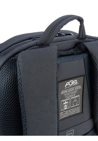 Donkergrijze rugzak met een gevoerd rugpaneel, een netstructuur en een prominente label die de functionaliteit van het Anti Gravity System (AGS) beschrijft.
