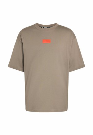 Nadrozměrné tričko krátkého rukávu v barvě taupe s malou oranžovou obdélníkovou nášivkou s logem umístěnou uprostřed na hrudi.