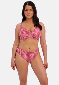 Rood-wit gestreepte bikini met een onderbuste beha en een hoog vergde broekje, voorzien van gouden hardwareaccenten op de tailleband.