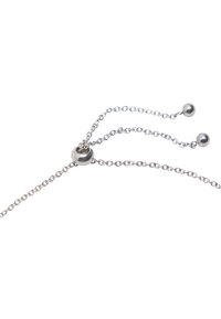 Srebrny łańcuszek z dwoma zwisającymi pasmami, każde kończy się okrągłą koraliką. Posiada okrągłą koralikę przesuwną do regulacji długości. Polerowane wykończenie.