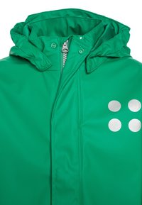 Giacca impermeabile verde con cappuccio, dotata di una cerniera argentata, bottoni a pressione e tre punti argentati sul lato sinistro. Texture liscia.