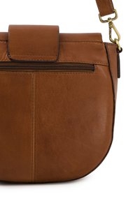 Brun læderhåndtaske med en rund form, der har en magnetisk klaplukning og en lynlås lomme foran, med en glat overflade.