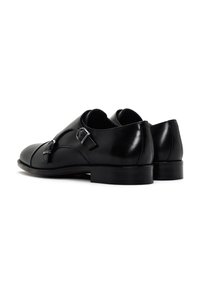 Zwarte leren schoenen met een ronde neus, voorzien van een enkele gesp en een lage, ronde hak. Gladde afwerking met minimale accenten.