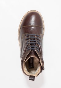 Hnědá kožená šněrovací bota s béžovým prošíváním, bočním zipem a viditelnou měkkou kožešinovou podšívkou uvnitř na bílém pozadí.