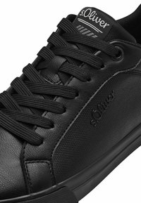 Schwarzer Sneaker mit strukturiertem Synthetik-Obermaterial, schwarzen Schnürsenkeln, Gummisohle und eingeprägtem s.Oliver-Logo auf der Seitenwand.