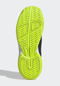 Semelle de chaussure en caoutchouc jaune vif avec un motif en chevrons, présentant une surface texturée et une semelle intermédiaire rembourrée.