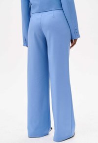 Lichtblauwe op maat gemaakte broek met een wijde pijpen-silhouet, voorzien van een gladde textuur en subtiele details op de achterzak.