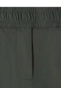 Ceinture en tissu gris foncé avec fronces élastiques et détail de couture sur un matériau doux, probablement une partie de vêtements décontractés.