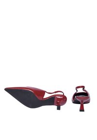 Tacchi slingback in pelle laccata rossa con punta affilata, un tacco sottile e un design minimalista, caratterizzati da un dettaglio di apertura sul tallone.