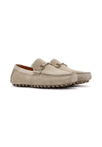 Mocasines de ante beige con puntera redonda, costuras decorativas y suela de goma con textura de guijarros. Presenta acentos metálicos en el empeine.