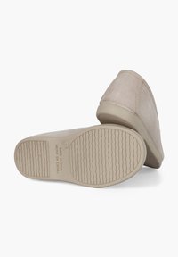 Beige Wildleder Slipper mit strukturierten Gummi-Sohlen, runder Zehenpartie und dezenten Nahtdetails. "Hergestellt in Spanien" auf der Sohle gedruckt.