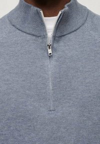 Hellblauer Pullover mit halbem Reißverschluss, strukturiertem Strick, geripptem Kragen und metallischem Reißverschlussdetail. Eng anliegendes Design, lässiger Stil.