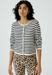 Gestreifter Cardigan in Marineblau und Creme, mit Rundhalsausschnitt, Knopfverschluss und 3/4-Ärmeln, kombiniert mit Hose im Leopardenmuster.