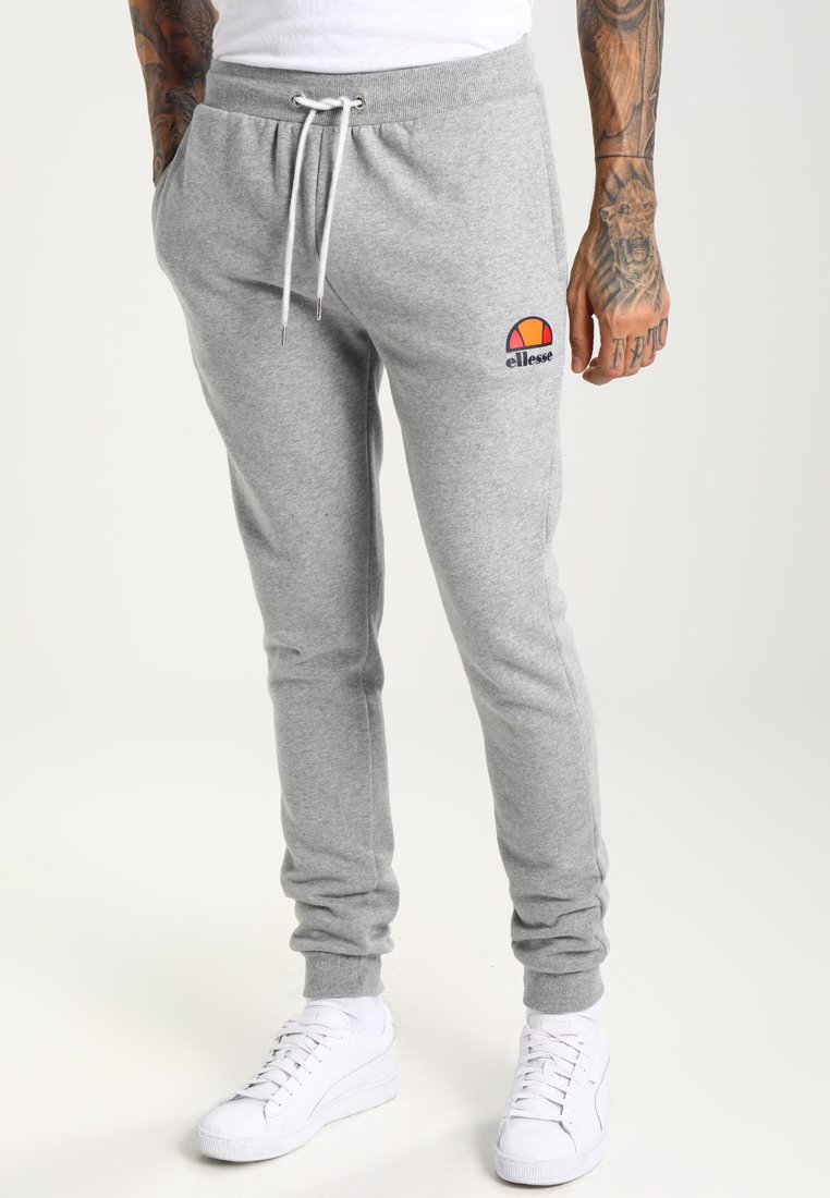 Pantalones de chándal grises con cintura elástica y cordón, que presentan un pequeño logotipo colorido en el muslo izquierdo. Material de algodón suave.