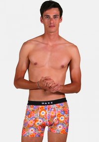 Caleçons boxers colorés ornés d'un motif floral dans des teintes d'orange, de rose et de bleu, avec une ceinture élastique noire portant l'inscription "WAXX".