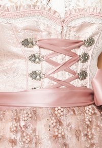 Roze brokaat korsettjurk met kantafwerking, decoratieve zilveren hardware, vetersluiting aan de voorkant, satijnen lint en parelversieringen op de rok.