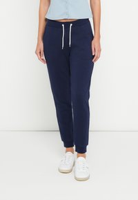 Calças jogger de algod�ão azul-marinho com punhos elásticos e cintura com cordão. Textura suave e ajuste descontraído, combinadas com ténis brancos.