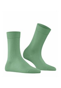 Chaussettes en coton vert clair avec une texture lisse, de longueur mi-mollet et une bordure côtelée. Présente un orteil sans couture et un design épuré et minimal.