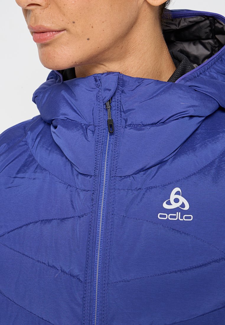 Lila isolierte Jacke mit hohem Kragen, Reißverschluss und einzigartigem Steppmuster. Verfügt über ein Logo auf der Brust und eine glatte Textur.