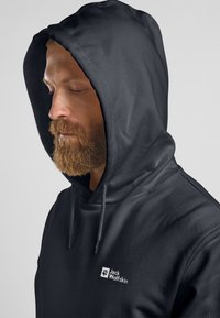 Schwarzer Hoodie aus glattem Stoff, mit einer Fronttasche und Kapuze mit Zugband. Zeigt ein weißes Logo auf der linken Brustseite.