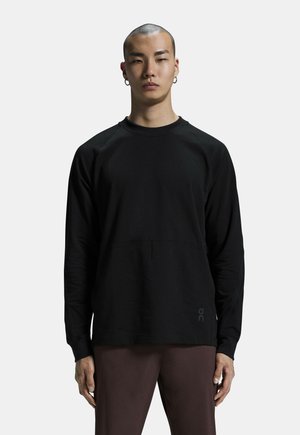 Zwarte long-sleeve shirt van zachte stof met een ronde halslijn en raglanmouwen, voorzien van een subtiele voortas en logodetail.