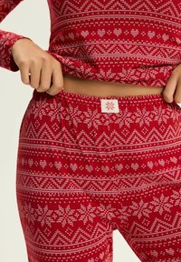 Czerwony zestaw odzieży domowej z wzorem w śnieżynki i serca, wykonany z miękkiego materiału. Elastyczny pas w talii z małą łatką z logo.