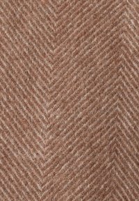 Textil con patrón de espiga en tonos marrones, que presenta una mezcla de lana suave y texturizada con sutiles acentos blancos y una sensación natural.