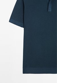Polo shirt a maniche corte di colore blu navy, con un motivo texturizzato e colletto semplice. Il tessuto presenta un aspetto a nido d'ape con dettagli a coste.