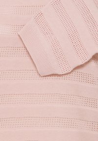 Tissu tricoté rose clair avec des rayures horizontales alternant entre un motif uni et un motif ajouré, montrant un poignet côtelé plié.