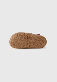Brun gummiyttersida med texturerat greppmönster; har präglad logotyp och siffror. Designad för grepp och hållbarhet.