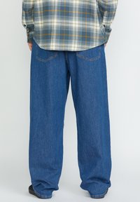 Pantalones vaqueros de denim de corte recto, holgados y de color azul claro, con dos bolsillos traseros y detalles de costura mínimos.