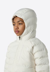 Λευκό μπουφάν με επένδυση και κουκούλα, με κεντρικό φερμουάρ, καπιτονέ υφή και λογότυπο στην πάνω αριστερή περιοχή.