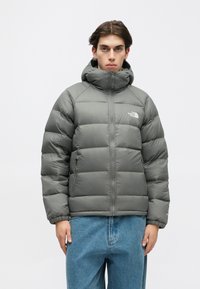 Szürke pufferek dzseki magas gallérral, cipzáros záródással és logóval díszített. Párnázott kivitelű, rugalmas mandzsettákkal a szigetelés érdekében.