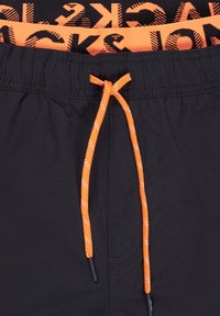Schwarze Badeshorts mit einem elastischen Bund, ausgestattet mit einer orangefarbenen Kordel und kontrastierendem Drucktext entlang des Bundes.
