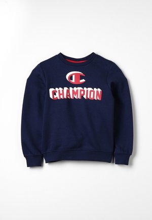 Granatowa bluza z długim rękawem z czerwonym i białym logo oraz emblematem "Champion" na środku klatki piersiowej.