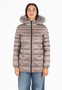 Giacca imbottita in morbido taupe con cappuccio foderato in pelliccia sintetica, dotata di zip frontale e polsini elasticizzati, abbinata a jeans di denim blu dal taglio morbido.