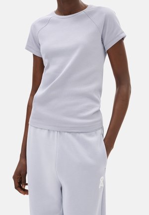 Przylegający, jasnoszary, prążkowany top z krótkim rękawem w zestawie z pasującymi jasnoszarymi spodnami dresowymi z małym białym logo na lewym udzie.